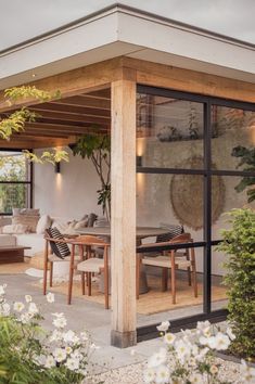 an outdoor dining area with wooden tables and chairs, surrounded by white flowers on the ground