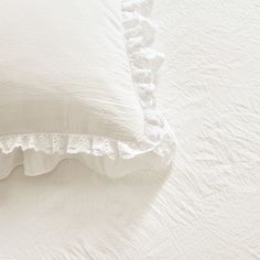 two white pillows with ruffled edges on a bed