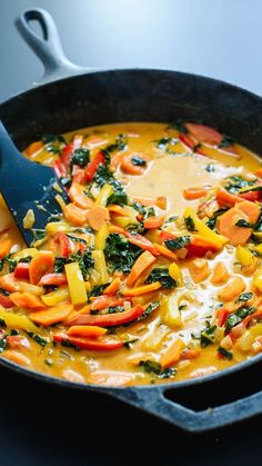 a pan filled with vegetables and cheese on top of a table next to a spoon