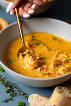 a person holding a spoon in a bowl of soup