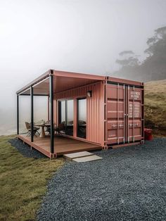 a large shipping container sitting on top of a grass covered hillside next to a picnic table