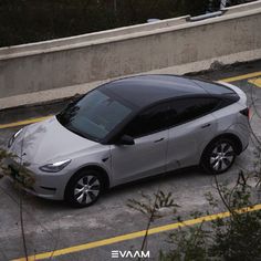 an electric car is parked on the side of the road in front of a concrete wall