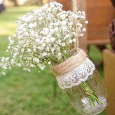 a mason jar filled with baby's breath sitting on top of a wooden bench