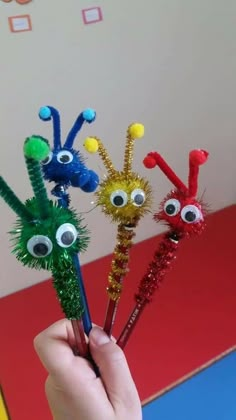 four colorful toothbrushes with googly eyes on them in a person's hand