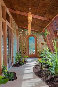 a walkway leading to an open air room with plants on either side and a large window in the middle