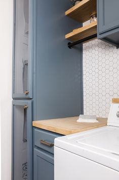 a washer and dryer in a small room with blue cabinets on the wall