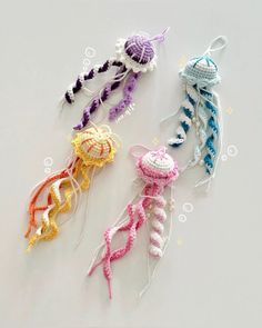 three crocheted jellyfish are shown on a white surface, one is multicolored