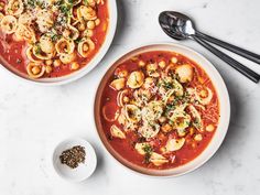 two bowls of pasta soup with spoons on the side