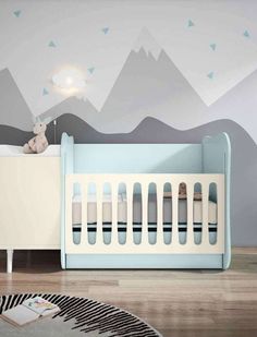 a baby's room with mountains painted on the wall and a crib in the foreground