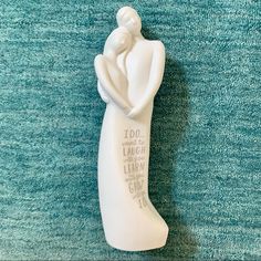 a white ceramic figurine with writing on the bottom and an image of a woman holding a child