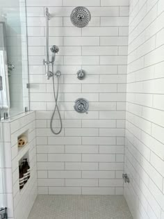 a walk in shower sitting next to a white tiled wall and floor covered with gray tile