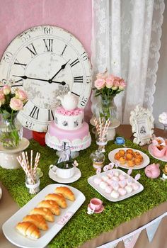 a table topped with cakes and pastries next to a clock