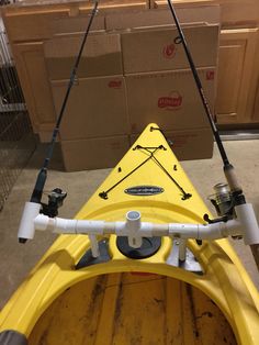 a yellow kayak with two fishing rods attached to the front and back ends, in a storage area