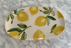 a plate with lemons painted on it sitting on a marble counter top, in front of a marble background