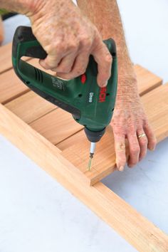 an older person uses a drill to cut wood planks with a cordless jig