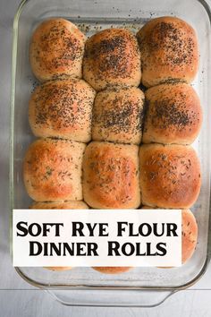 a glass dish filled with rolls covered in poppy seed sprinkles next to a sign that says soft rye flour dinner rolls