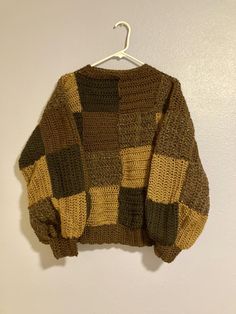 a brown and yellow sweater hanging on a white wall