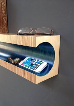 a wooden shelf with a cell phone and glasses on it