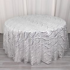 a round table with white and black zebra print on the top, sitting in front of a curtain