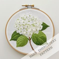 a hand embroidered white flower with green leaves