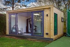 a small wooden shed with sliding glass doors on the outside and an exercise room in the inside