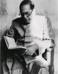 an old photo of a man sitting in a chair with a book on his lap