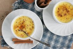 two white plates topped with soup next to cinnamon sticks and an orange juice in a cup