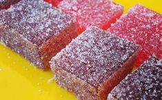 four pieces of cake sitting on top of a yellow plate covered in powdered sugar