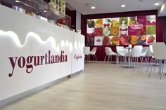 the interior of a yogurt shop with white chairs and colorful signs on the wall