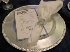 a silver plate topped with a white napkin and a dinner menu on top of it