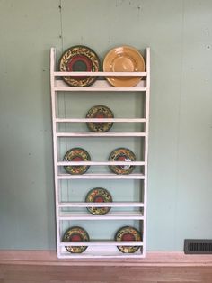 a white shelf with plates on it in a room that has blue walls and wood flooring