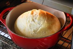 a loaf of bread in a red pot on an oven rack