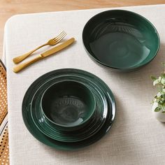 two green plates sitting on top of a table next to a vase with flowers in it