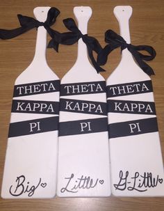 three white paddles with black ribbon tied around them on top of a wooden table