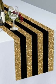 there is a wine glass and bottle on the table with black and gold striped napkins