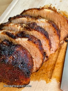 sliced pork on cutting board with knife next to it