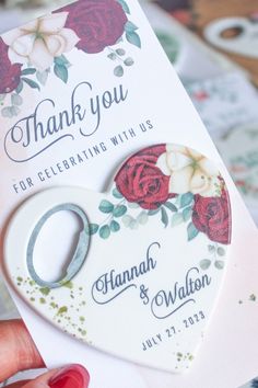 a hand holding a wedding card with a heart shaped keychain attached to it