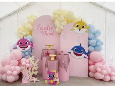 a pink and blue birthday party with balloons, decorations and shark figures on the wall