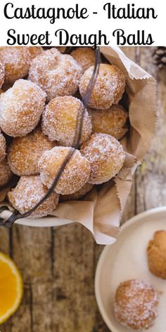 there is a bowl full of doughnuts on the table with orange slices next to it