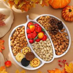 two serving trays filled with nuts, fruit and veggies on top of a table