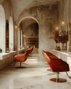 the interior of a modern salon with red chairs and marble counter tops, an arched doorway leading to another room