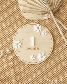 a wooden clock sitting on top of a table next to some flowers and an umbrella