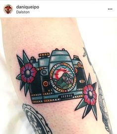 a tattoo with a camera and flowers on it