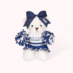 a white teddy bear wearing a blue cheerleader outfit and holding a pom pom