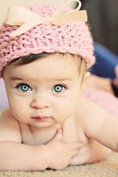 a baby wearing a pink knitted hat with a bow on it's head