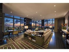 a living room filled with lots of furniture and large windows overlooking the city at night