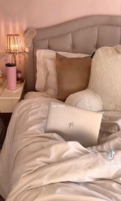 a laptop computer sitting on top of a bed next to two nightstands with lamps