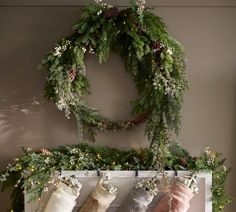 stockings hung on a mantle with christmas wreaths and greenery around the fireplace mantel