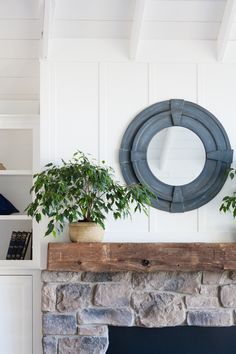 a living room with a fire place and potted plants on top of the mantle