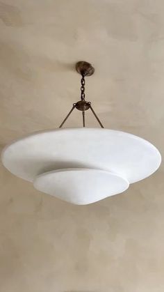 a light fixture hanging from the ceiling in a room with beige walls and flooring